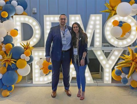Politheon co-founders Daniel Forcade and Hannah Bodnar stand in front of a lighted sign reading "Demo Day" at the CREATE-X Demo Day in August 2025.